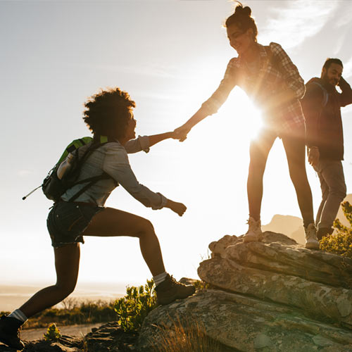 Millennial hikers helping each other to the summit