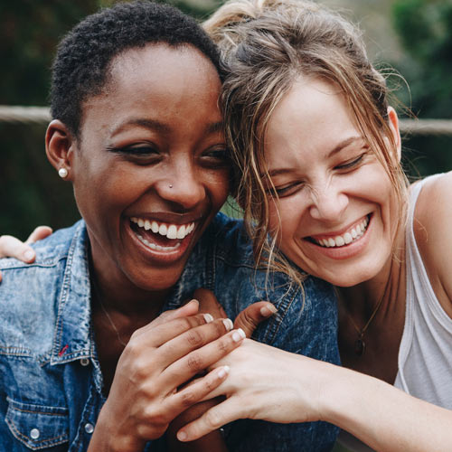 Two millennial friends laughing and sharing a private moment